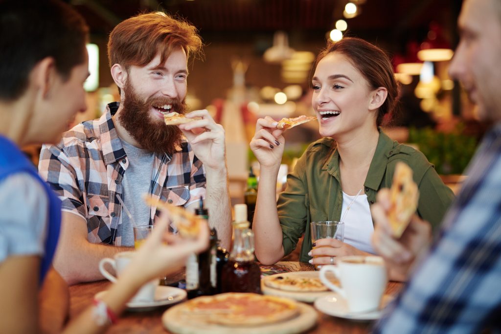 Joyful,Friends,Gathered,Together,In,Pizza,Restaurant,And,Chatting,Animatedly